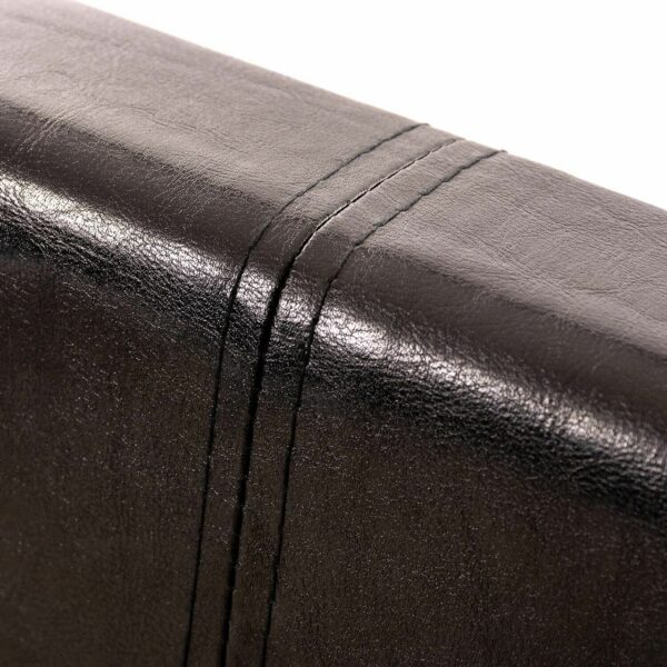 The headboard of a black faux leather bed