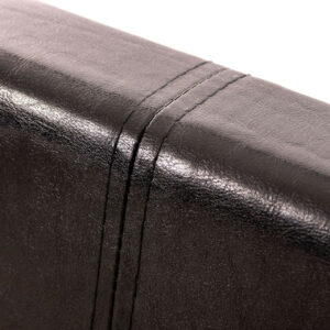 Top of the headboard of a black faux leather ottoman bed