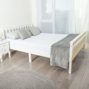 A white double wooden bed in a white bedroom