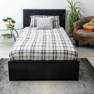 Front view of a black single faux leather ottoman bed with patterned sheets