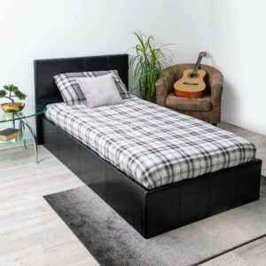 Side view of a black faux leather ottoman bed with checked sheets