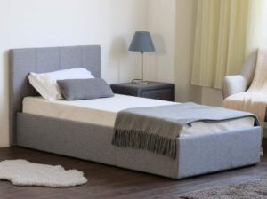 Side view of a closed grey ottoman bed with a blanket on it