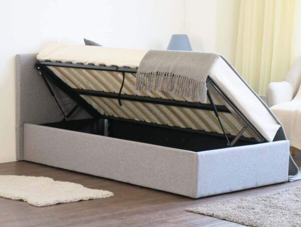 A grey ottoman bed opened up for storage